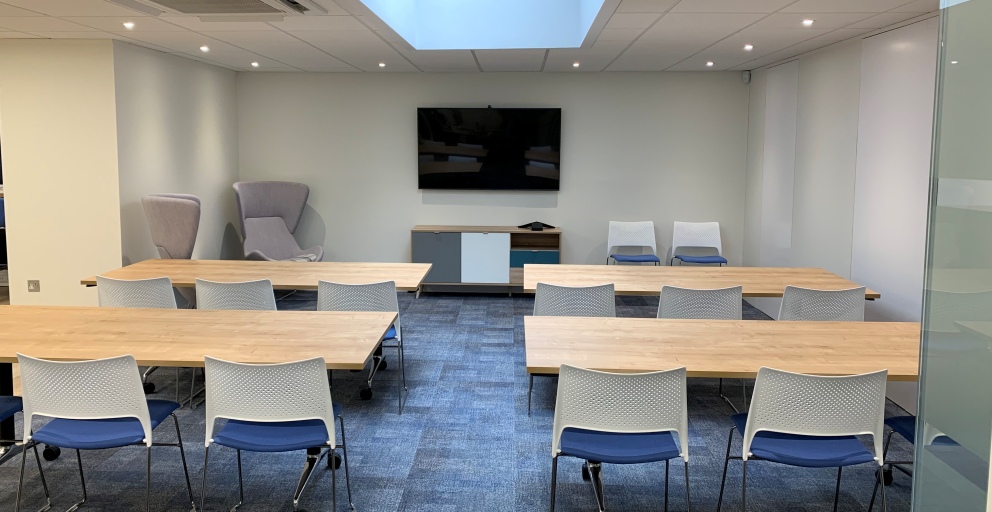 Multifunctional office space with tables chairs and wall mounted screen 