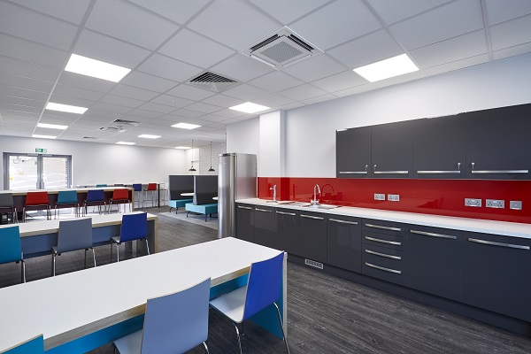 Staff kitchen area with grey kitchen cabinets, red splashback and high tables and chairs