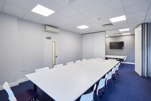 White meeting room take and white chairs in a white room with blue carpet